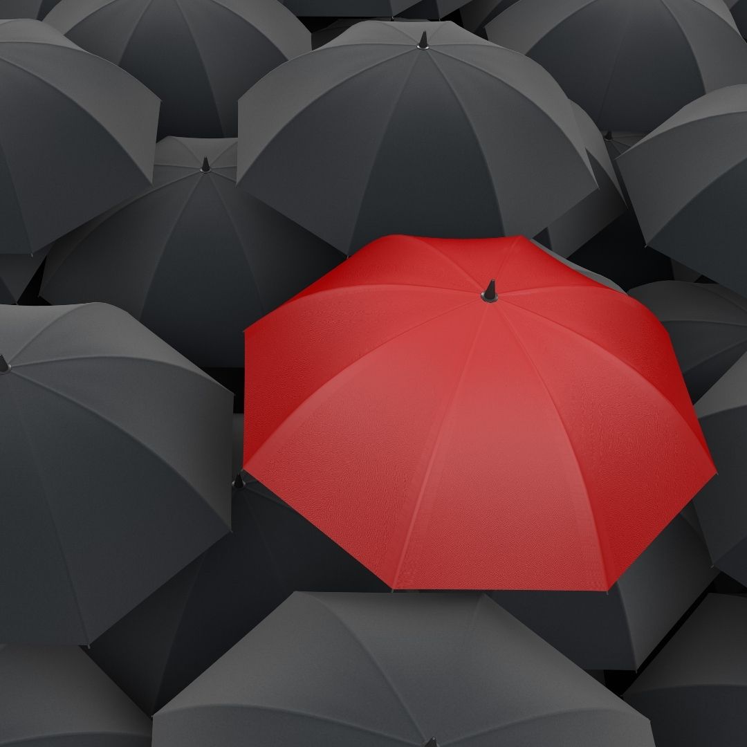 A red umbrella open in a sea of grey umbrellas