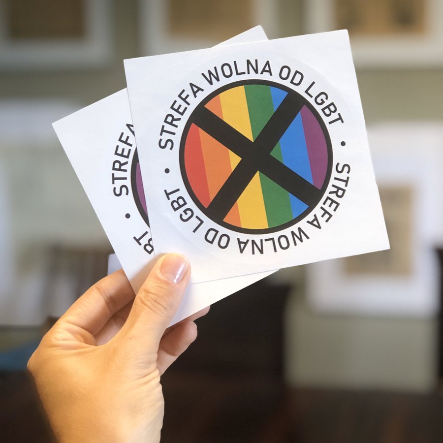 A hand holding LGBTI Free Zone stickers in Poland