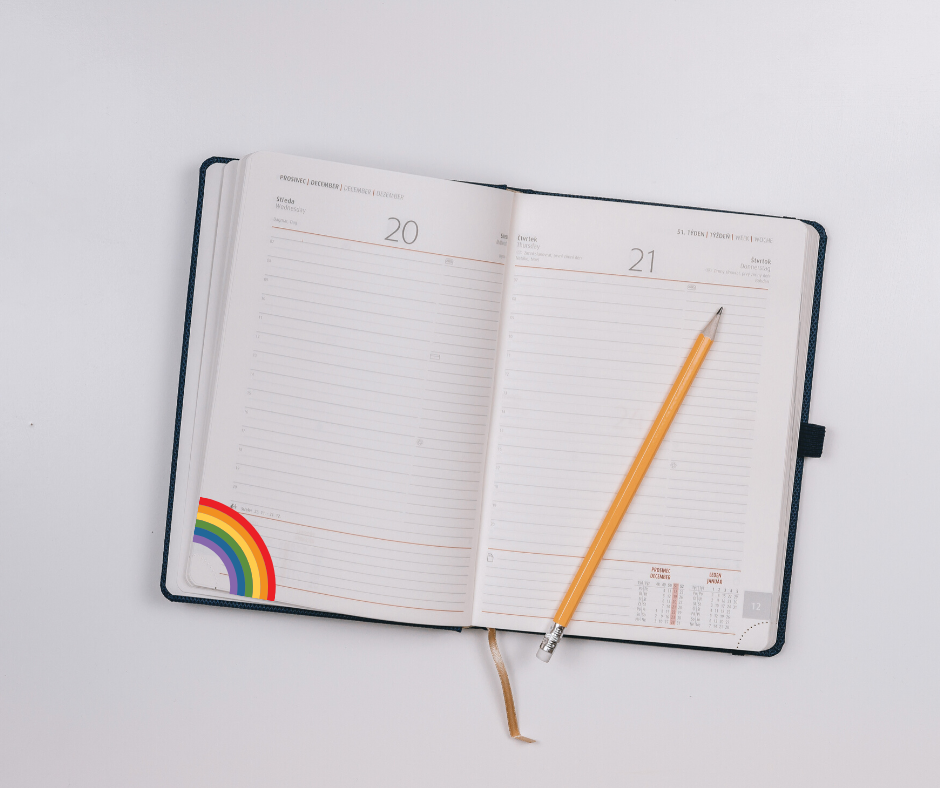An agenda with a pencil and a rainbow on a corner