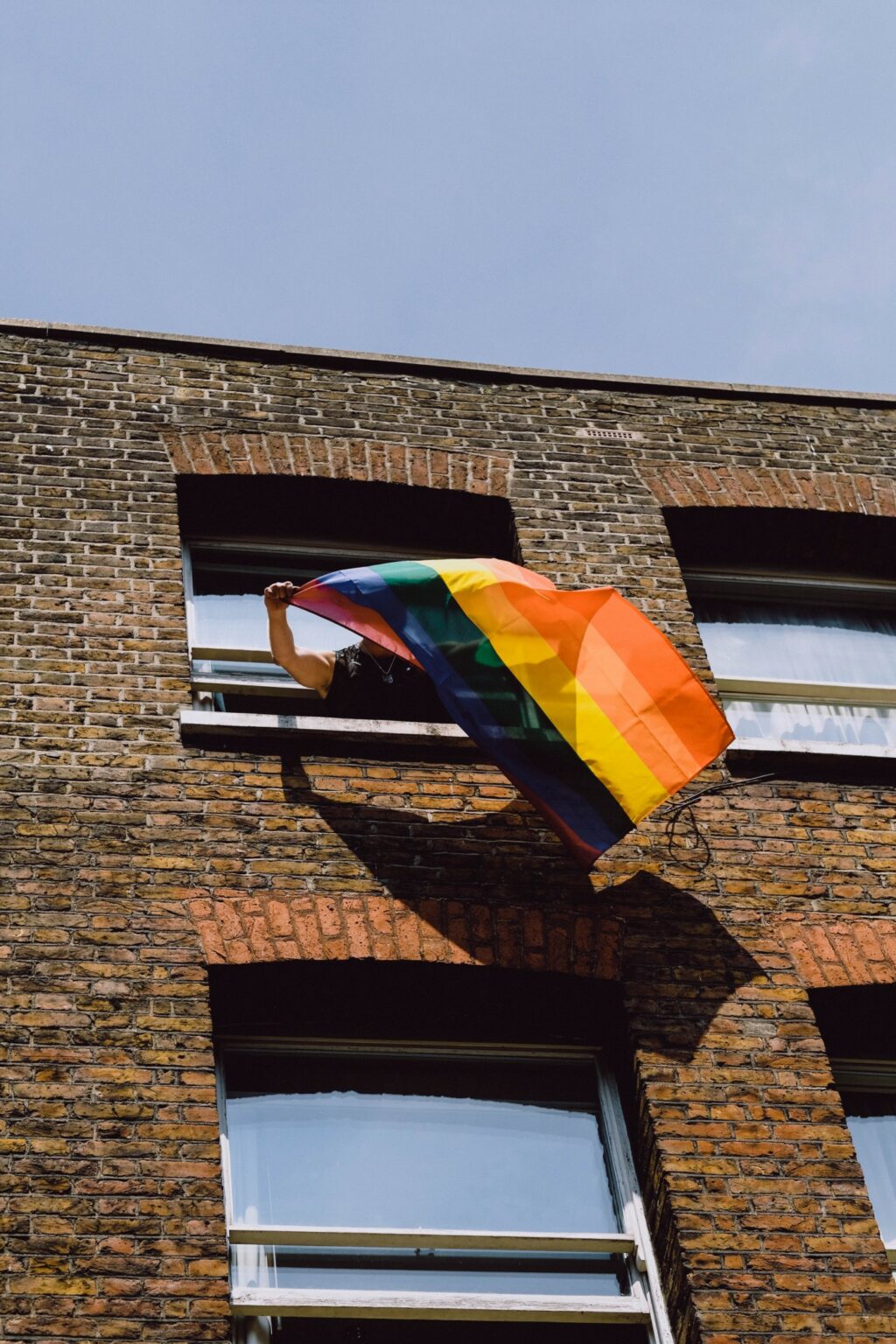 A rainbow flag blowing from a window