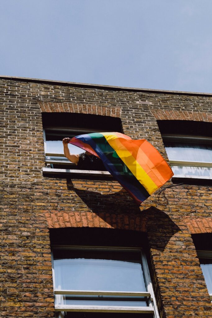 A rainbow flag blowing from a window