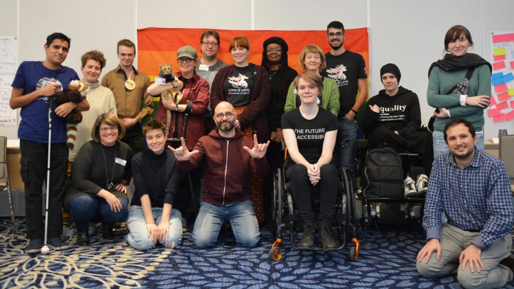 A moment of ILGA-Europe’s first Gathering of D/deaf and Disabled LGBTI Activists in 2019 showing a group of people smiling to the camera.