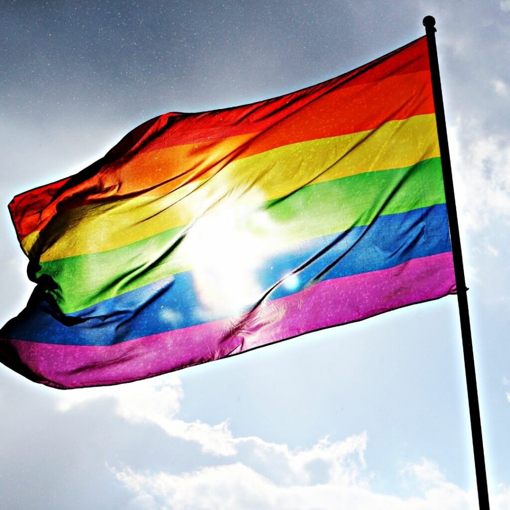 A rainbow flag flies against a blue sky