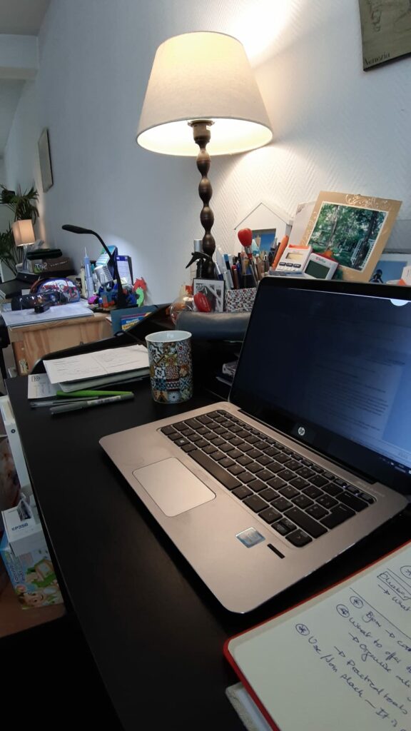 A desk with a laptop, a lamp and other objects