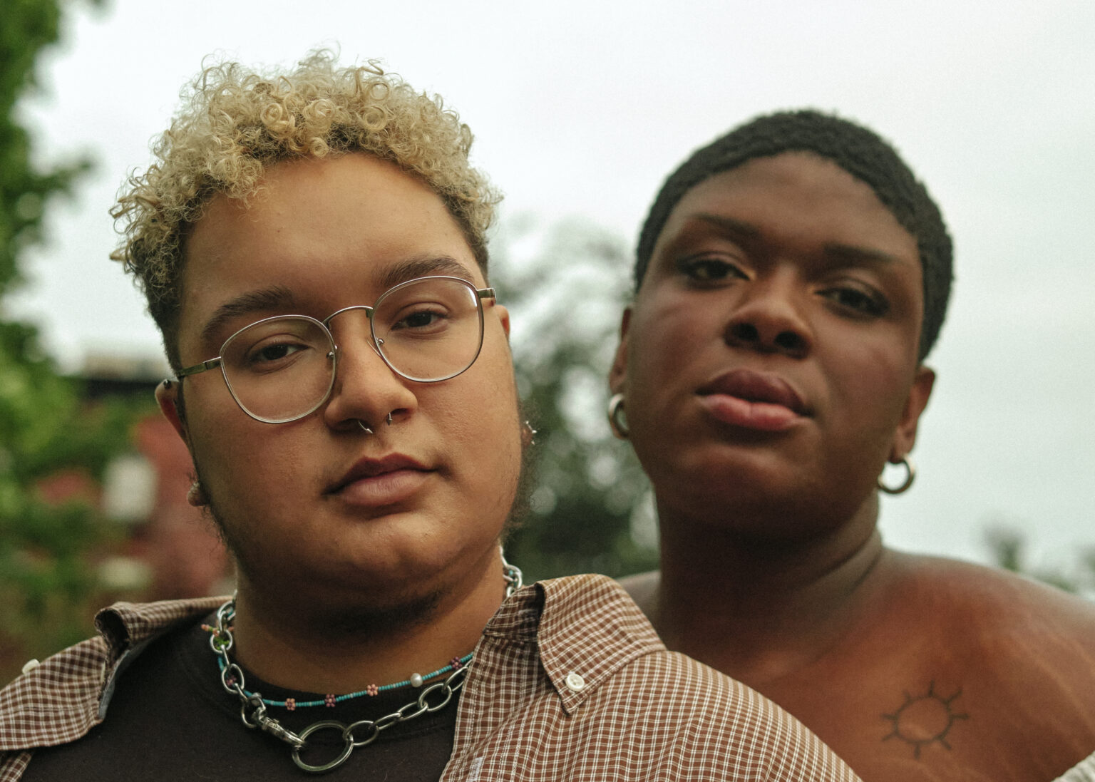 A transmasculine non-binary person and non-binary trans woman standing next to each other outside