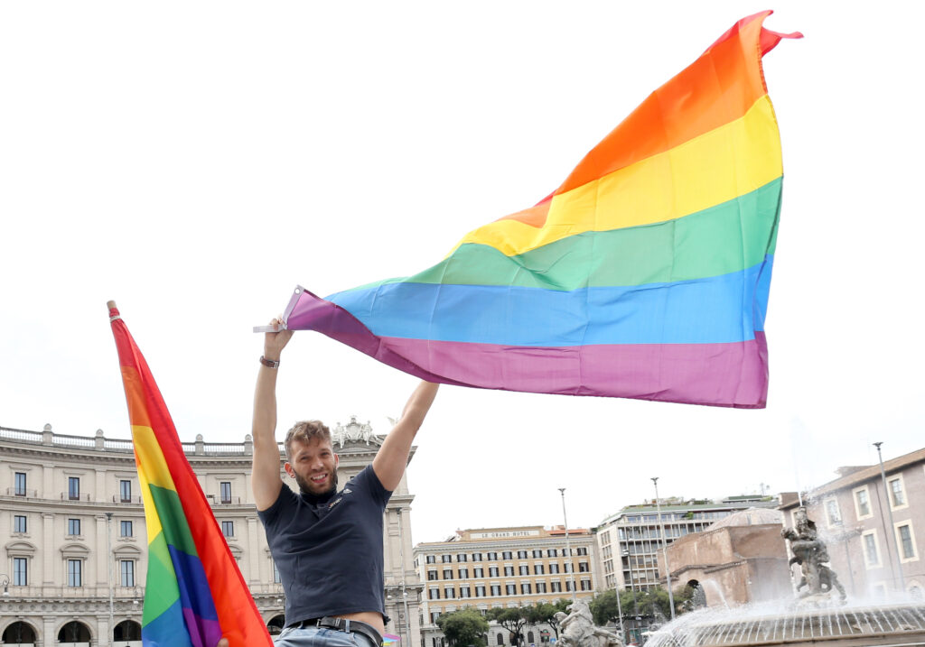 A young man waving a rainbow flag