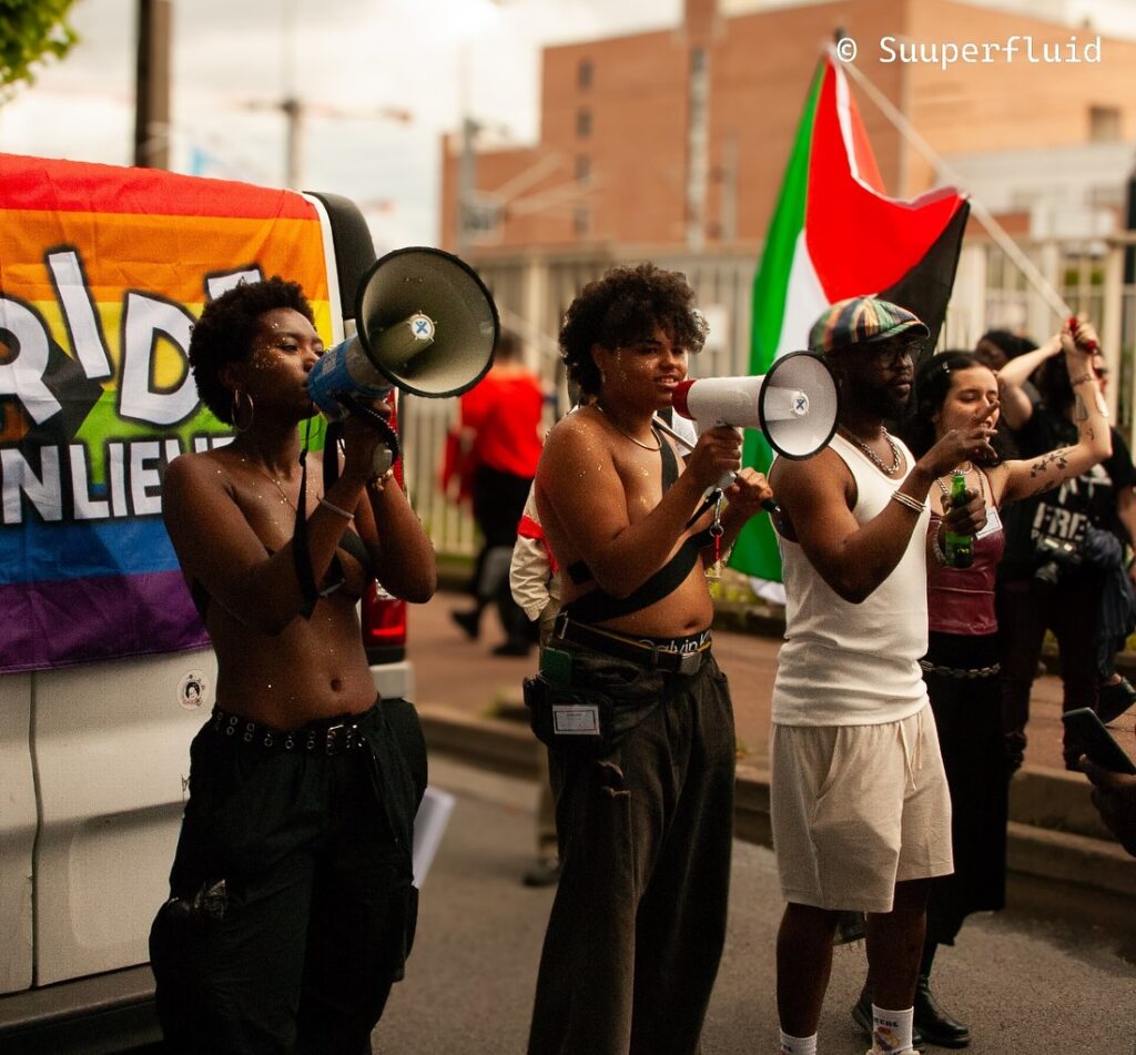A group of people are standing in front of a van during a Pride des Banlieues event.